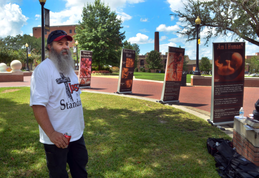 Pro-life protestor Johnny Brekeen stands amongst the anti-abortion signs being displayed on the USM campus near the fountain on Tuesday afternoon. | Photo by A.J. Stewart