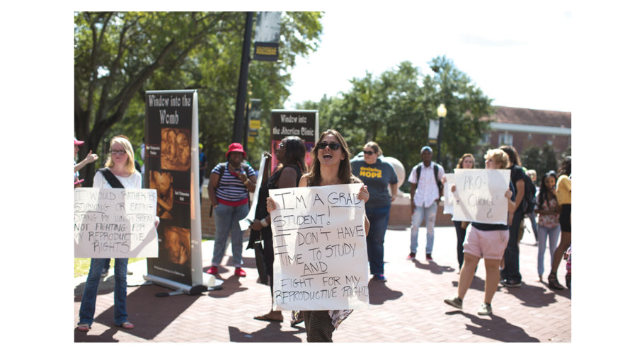 Brady+Leatherwood+protest+with+the+women%E2%80%99s+rights+advocates+in+Shoemaker+Square+Wednesday+afternoon.+Students+gather+around+in+between+classes+to+watch+the+anti-abortion+activists+that+frequent+the+Southern+Miss+campus.