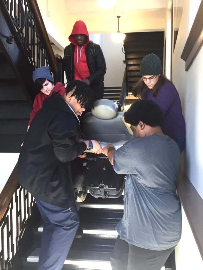 Students carry classmate’s wheelchair down three flights of stairs.