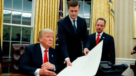 White House Chief of Staff Reince Priebus, right, watches as White House Staff Secretary Rob Porter, center, hands President Donald Trump a confirmation order for James Mattis as defense secretary, Friday, Jan. 20, 2017, in the Oval Office of the White House in Washington. (AP Photo/Evan Vucci)