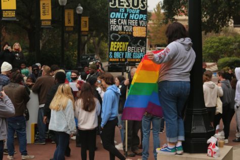 A student waves a Pride flag last semester as protestors preach anti-LGBTQ sentiments. (Photo/Sarah Kofman)