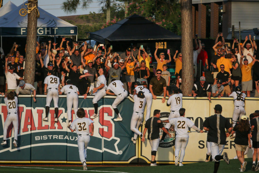 The+team+jumps+over+the+right+field+wall+to+celebrate+winning+the+2022+Hattiesburg+Regional+