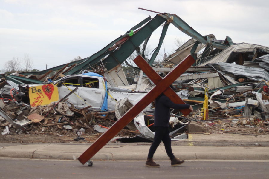 Dan Beazley carries a wooden cross in front of debris in Rolling Fork, Mississippi on March 31, 2023.
