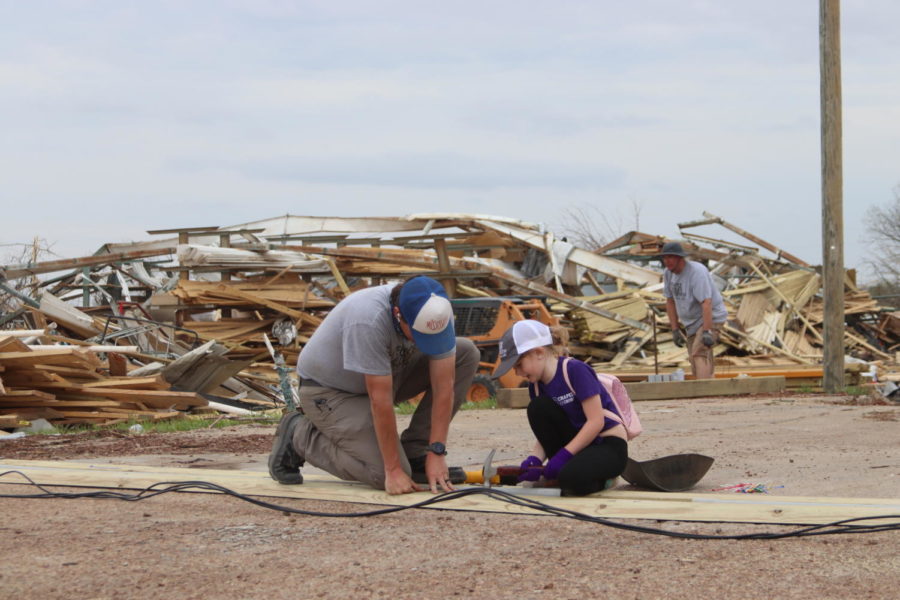 Brett Bailess, left, general manager of Service Lumber Company, holds a wooden board in place and supervises his daughter Kennedy Bailess, right, as she hammers nails as apart of the local recovery effort.