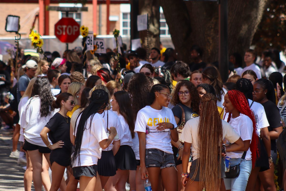 The student body gathers on the corner of the street while waiting for The Pride of Mississippi to march down the street.