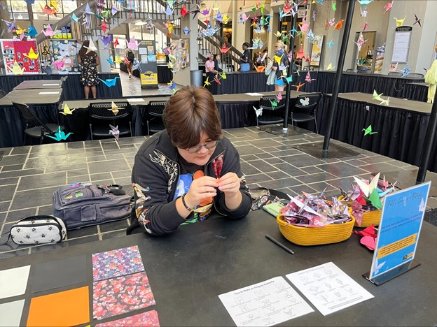 USM student, Theo Pierce completes origami paper cranes that other students started.