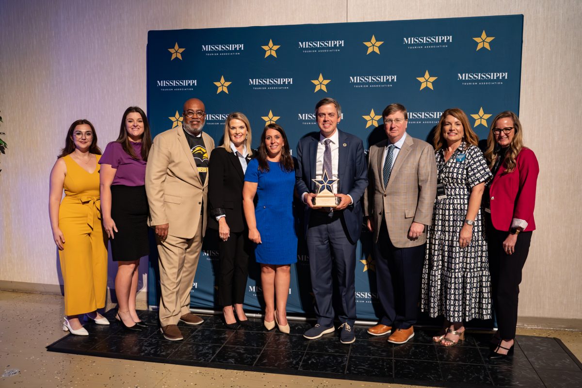 Hattiesburg Mayor Toby Barker hold a plaque recognizing him for his tourism efforts, as he is surrounded by state and local tourism officials.