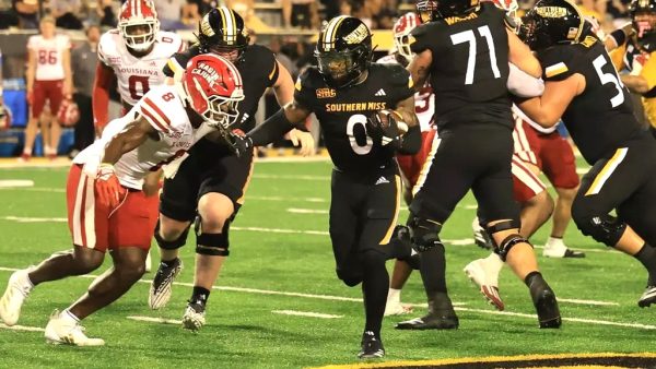 Southern Miss Golden Eagles running back Rodrigues Clark (0) runs between the tackles in the team's recent game against the Louisiana Ragin Cajuns.