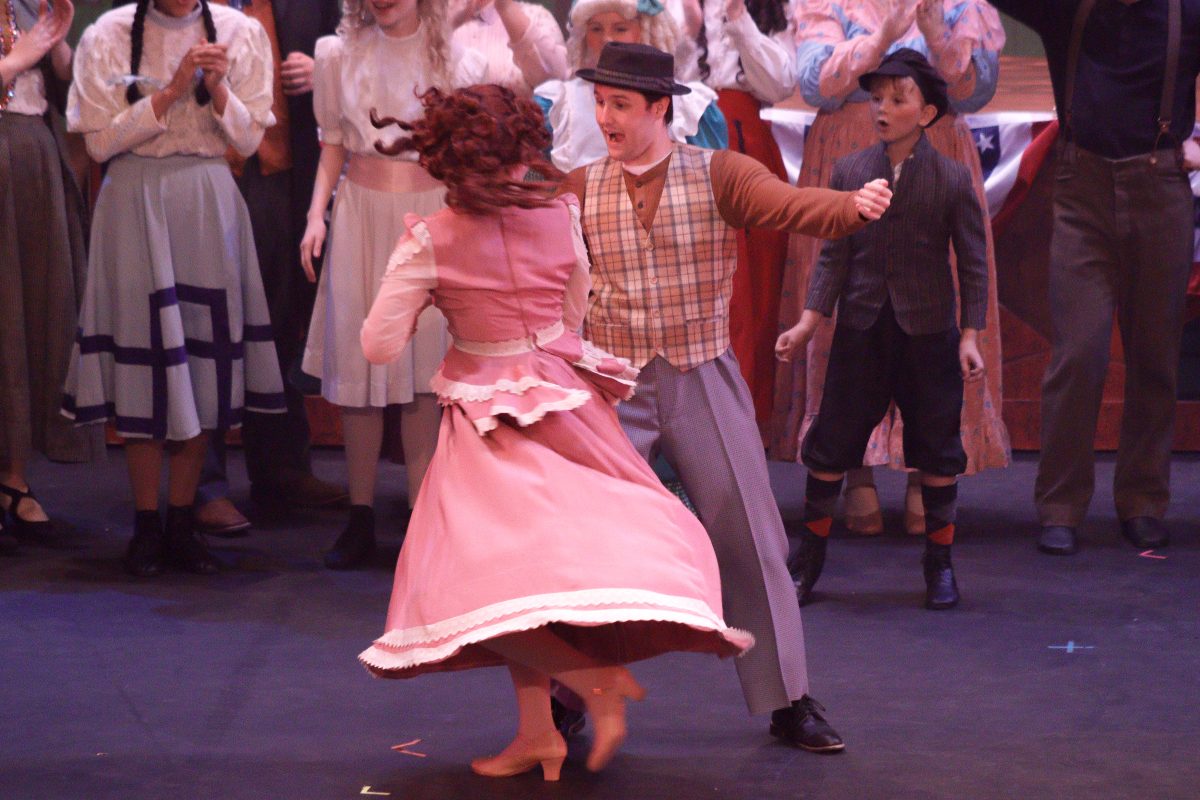 Marcellus Washburn (Hutson Rollins) dances with one of the townspeople as the town is swept into a storm of new beginnings.