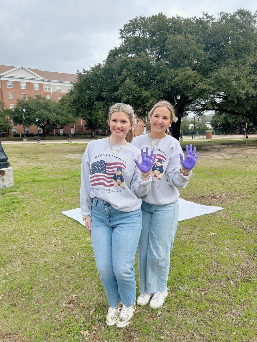 Members of Alpha Chi paint a banner with the USM community in Spirit Park 