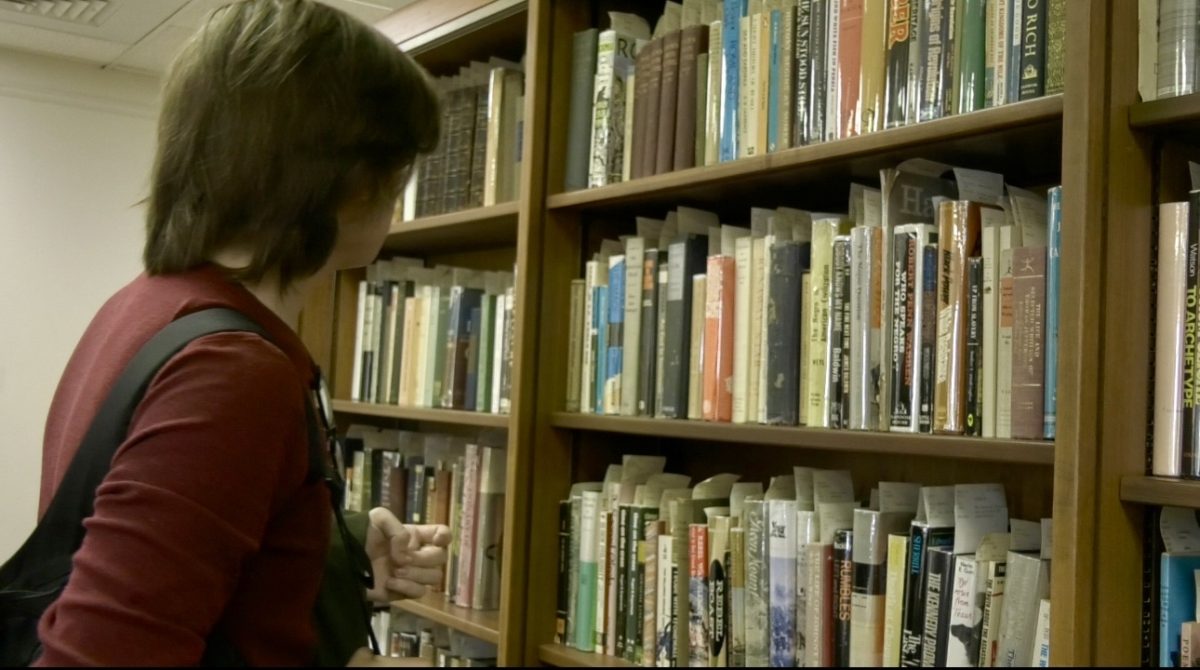 A USM student searches for a book in the library.