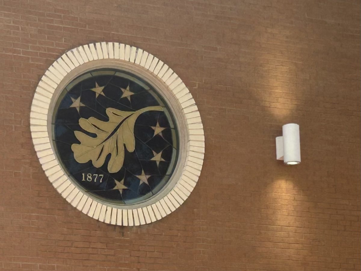 The Gold Leaf Society's logo, a golden oak leaf encircled by seven golden stars and "1877." This logo is located on the side of the Southern Station Stage at Spirit Park.