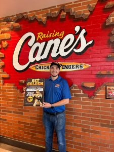 Hattiesburg Raising Cane’s Restaurant Leader Miles Underwood with the Golden Plush Puppy.
