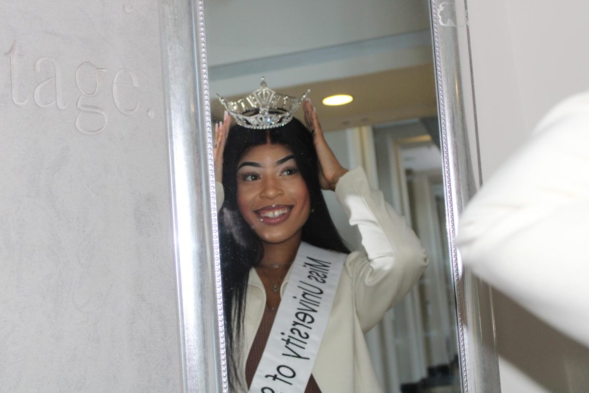 Alea Hudson smiles as she adjusts her crown in the mirror. 